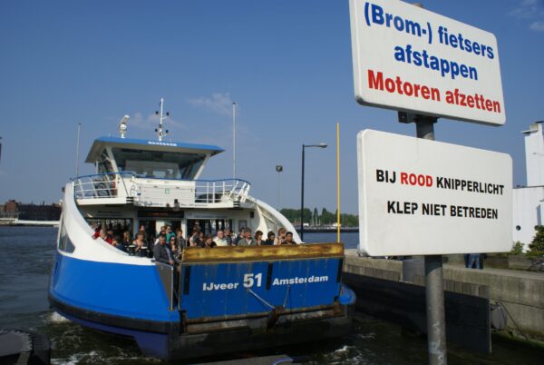 Moter en passagier stappen op veerpont naar Amsterdam Noord.