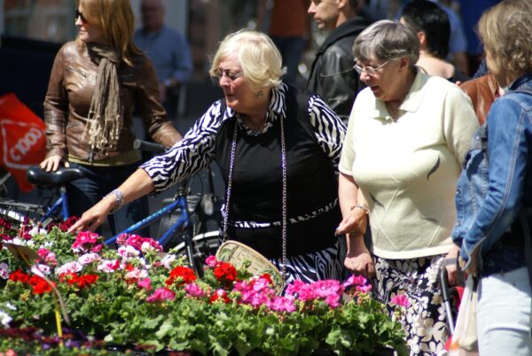 Dames kiezen bloemen op de markt.