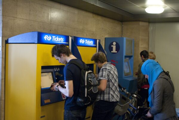 Mensen kopen treinkaartje bij NS-kaartautomaat Amsterdam Centraal.