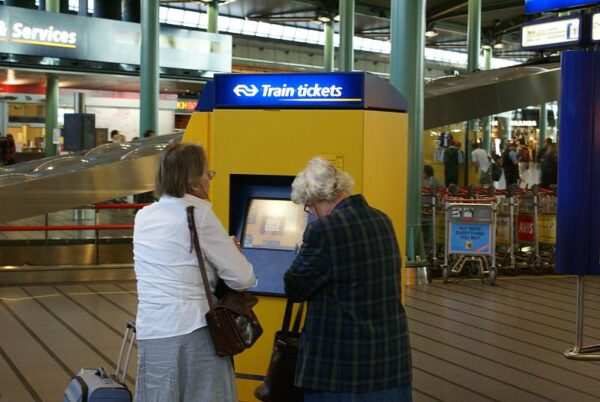 Twee vrouwen kopen treinkaartjes op Schiphol Plaza.