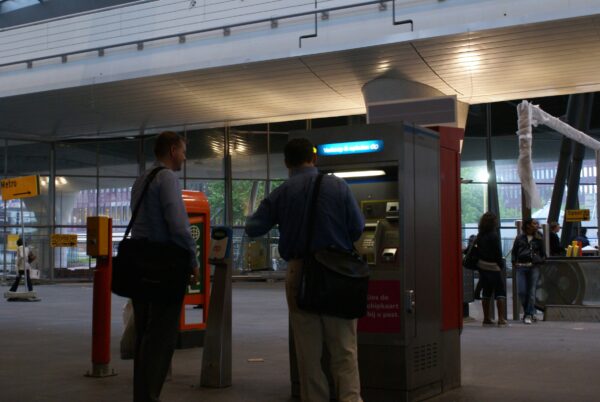 Mannen kopen OV-kaartje bij GVB-automaat.