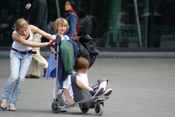 Rennende kinderen met bagagewagen op Schiphol.