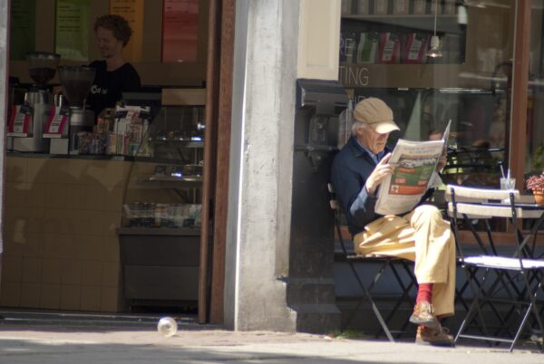 Man leest krant voor koffiezaak Pijp.