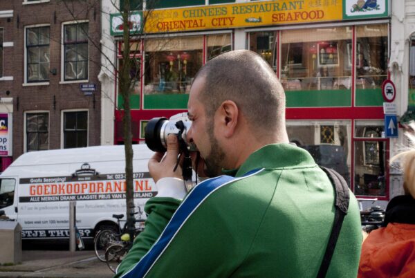 Man fotografeert doorkijk Oudezijdsvoorburg, Amsterdam.