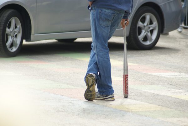 Boef met knuppel wacht bij autoraam, politiedemonstratie.