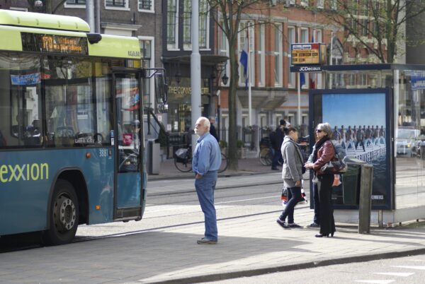 Man wacht bus 170 bij Nieuwezijds Kolk.
