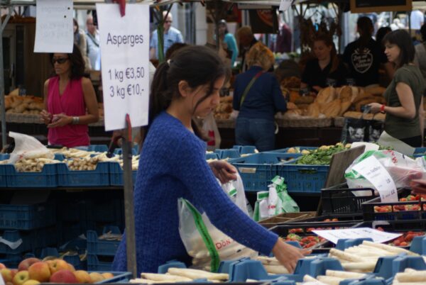 Meisje verkoopt asperges op markt.