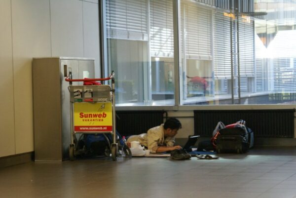 Laptop opladen in verborgen stopcontact tijdens wachten.