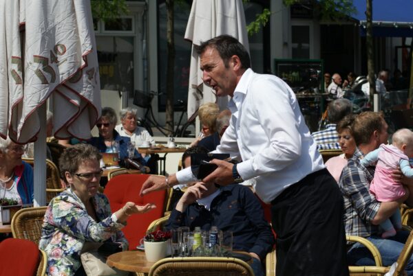 Ober geeft geld terug aan vrouw op terras Markt.