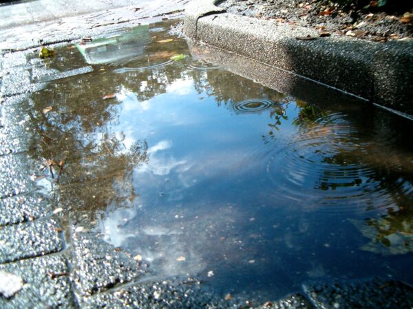 Regenwater stroomt in de goot.
