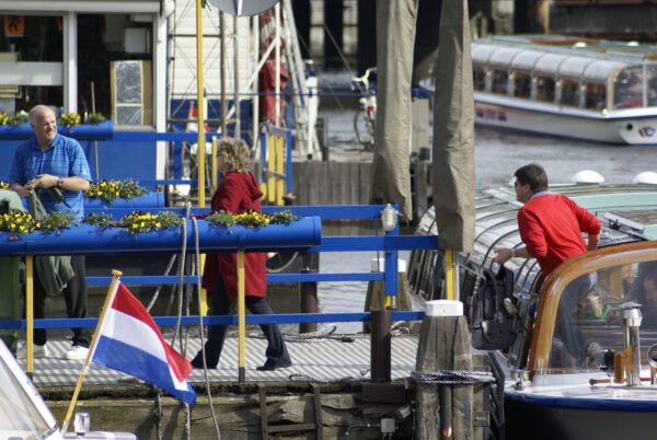 Toeristen stappen uit rondvaartboot Damrak, Amsterdam.