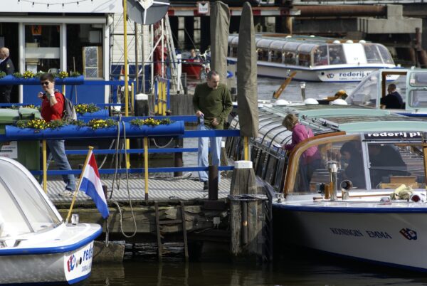 Toeristen stappen uit rondvaartboot, Damrak, Amsterdam.