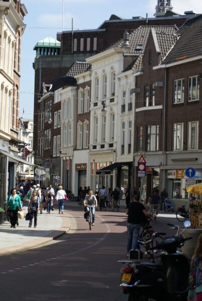 Fietser en winkelaars op de Schapenmarkt in Den Bosch, met rijksmonumenten.