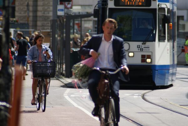 Fietsende jongen met bloemen, meisje belt in Amsterdam.