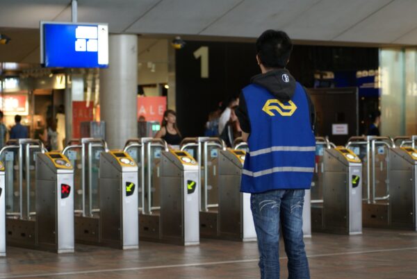 Jong NS-medewerker houdt toezicht bij OV-chipkaartpoortjes Rotterdam Centraal.