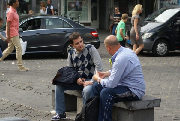 Twee mannen praten op een bankje.