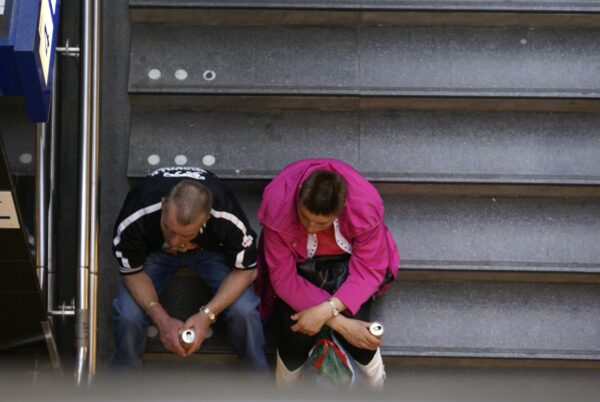 Twee mannen wachten op de trap bij Centraal Station.