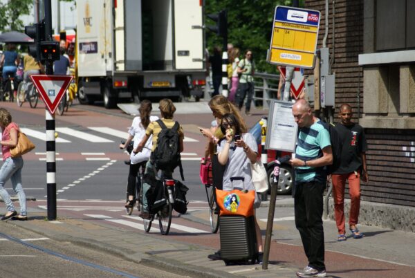 Vrouw geniet van ijs wachtend op tram, fietsende vrouwen in de Pijp.