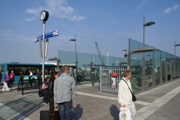 Mensen wachten op de bus bij Amsterdam Centraal.