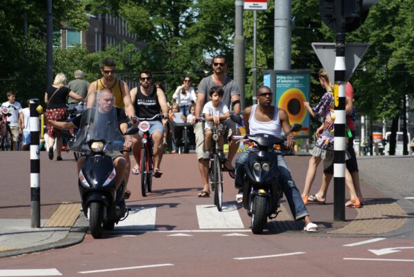Scooters en fietsers wachten op groen bij Stadhouderskade, Amsterdam.