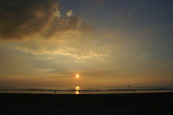 Zonsondergang Wijk aan Zee, boot en strandgangers.
